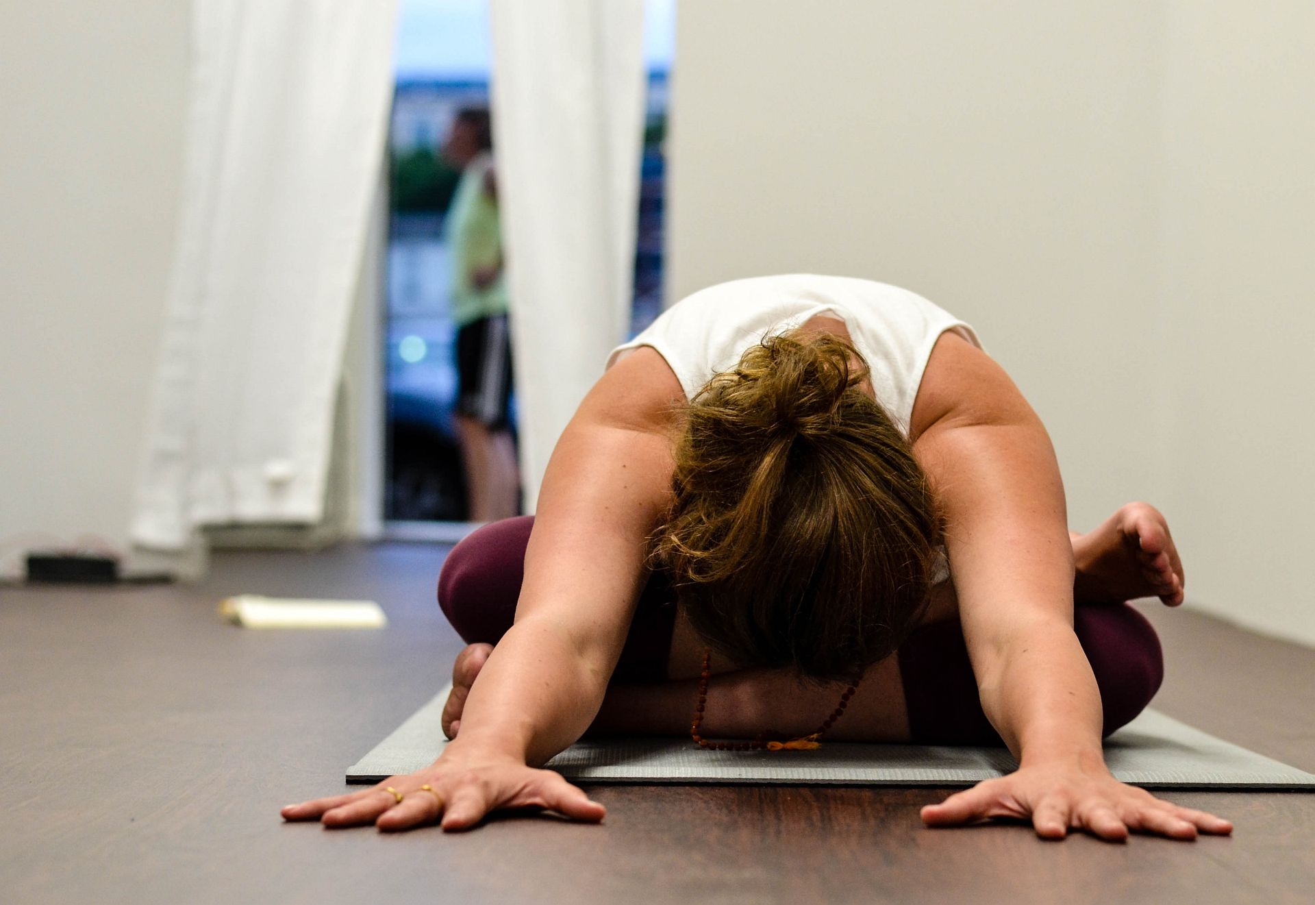 Eine Frau führt eine Yogaübung zur Muskelentspannung auf einer Yogamatte am Boden aus.