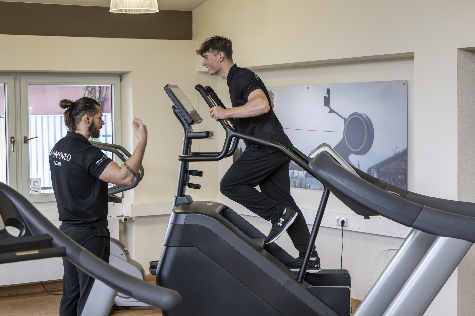 Trainer motiviert Mitglied beim Ausdauertraining auf dem Stufengerät für optimale Ergebnisse
