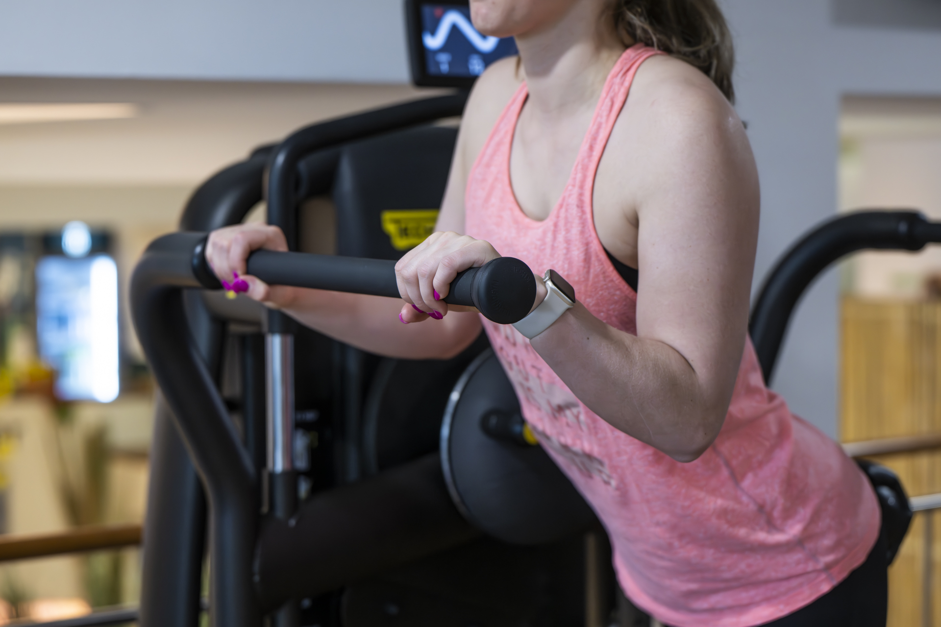 Eine Frau trainiert an einem Gerät in der Powerarea des PROMOVEO Fitnesszentrums.